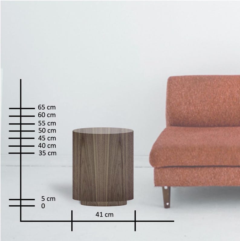 May include: A cylindrical wooden side table, approximately 25.6 inches tall and 16.1 inches wide, with a dark wood grain finish. The table has a slightly wider base. A coral-colored sofa is partially visible in the background.