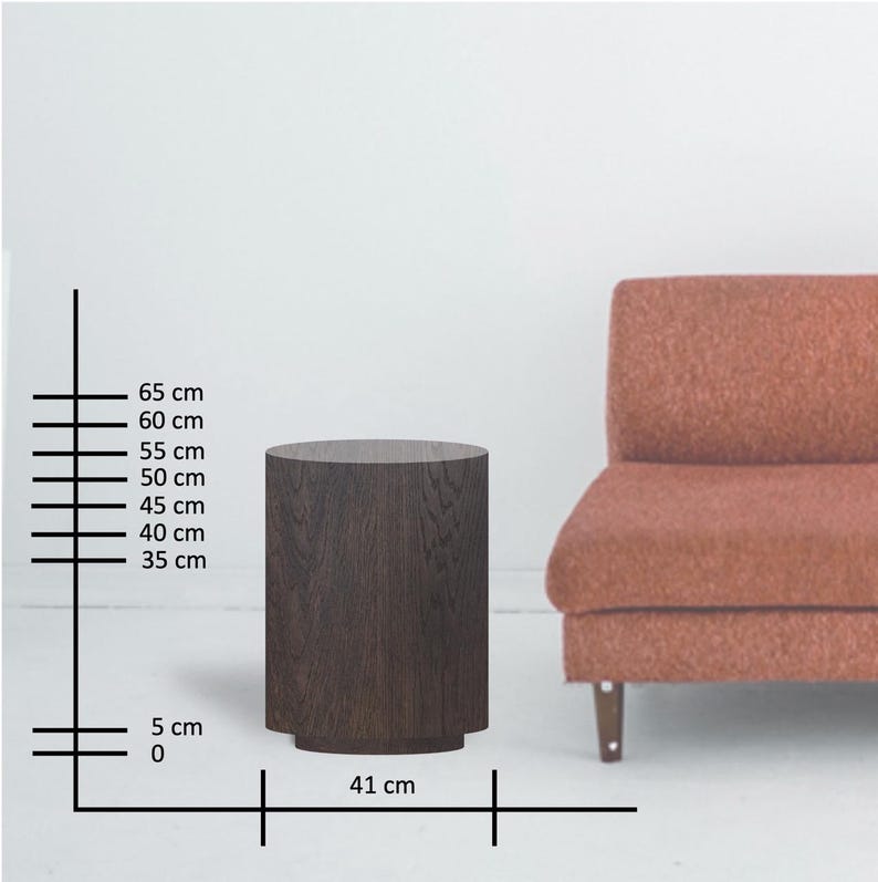 May include: A dark brown, cylindrical side table with a slightly flared base. The table is approximately 25.6 inches tall and 16.1 inches wide. The table is next to a rust-colored sofa.