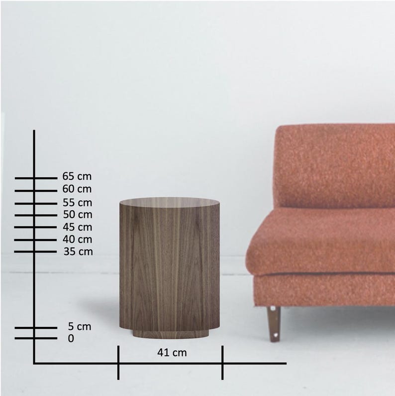 May include: A cylindrical wooden side table with a dark wood grain finish. The table is 16 inches in diameter and 26 inches tall. A rust-colored sofa is partially visible in the background. The table is a modern furniture piece.
