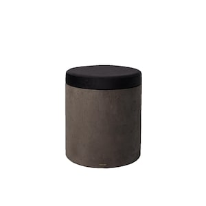 Könnte beinhalten: Ein zylindrischer Hocker mit einer dunkelgrauen, strukturierten Betonbasis und einem runden, schwarzen Samtsitz. Das moderne Design zeichnet sich durch eine neutrale Farbpalette aus, die für verschiedene Einrichtungsstile geeignet ist. Der Hocker ist etwa 46 cm hoch.