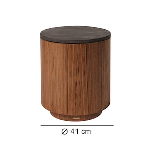 May include: A cylindrical side table with a dark gray top and a wooden base. The table has a diameter of 16 inches. The wood grain is visible on the sides of the table, adding a natural aesthetic.
