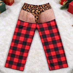 Puede incluir: Pantalones de estar por casa con un patrón de cuadros rojos y negros en las piernas y un estampado gráfico de un tanga de leopardo sobre glúteos de color carne en la cintura. Los pantalones son de tela lisa y tienen corte recto.