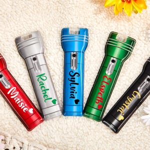 May include: Five personalized flashlights with different names on them. The flashlights are red, blue, green, silver, and black.