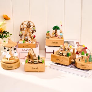 Pu&ograve; includere: Una collezione di carillon in legno con vari temi, tra cui una ruota panoramica, una giostra e un treno. Ogni scatola presenta dettagliate figure in miniatura ed &egrave; realizzata in legno chiaro. Alcune scatole hanno nomi incisi.
