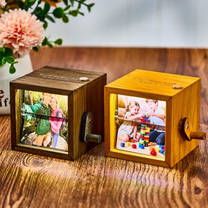 May include: Two wooden photo cubes with illuminated pictures. One is dark brown with the text "You're the best dad in the world!". The other is light brown with the text "I love you with all my heart!". Each has a hand crank.