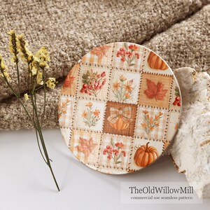 Peut inclure: Un dessous de verre rond en c&eacute;ramique pr&eacute;sentant un motif en damier avec des illustrations sur le th&egrave;me de l'automne, incluant des citrouilles orange, des baies rouges et des feuilles d'&eacute;rable brunes. Le texte TheOldWillowMill commercial use seamless pattern est imprim&eacute; en bas.