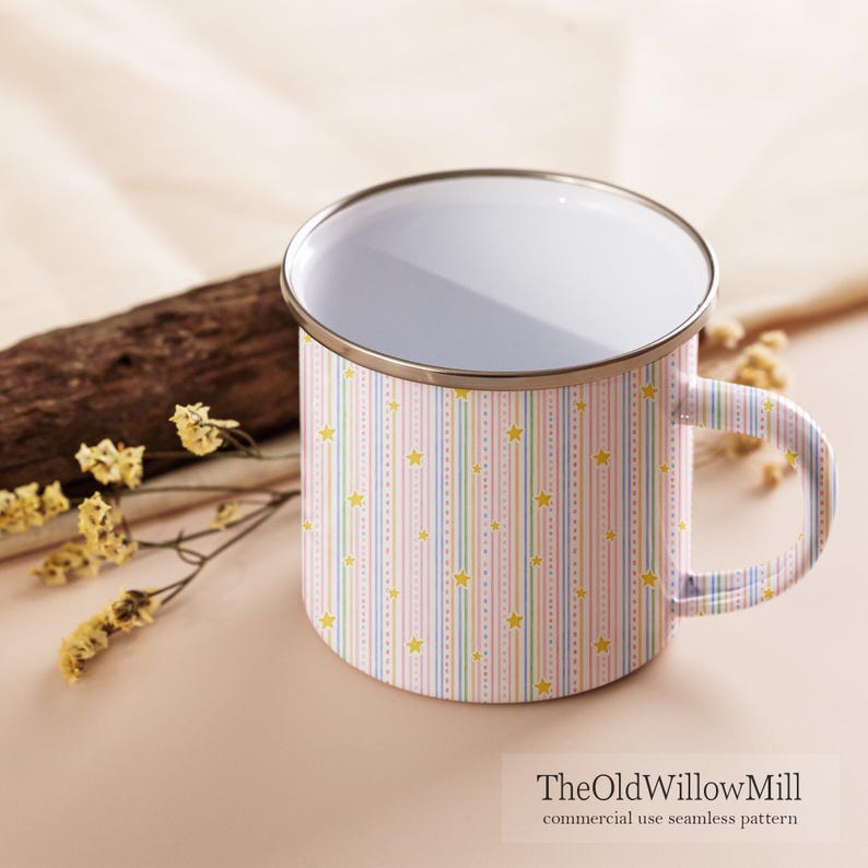 Puede incluir: Una taza de esmalte blanco con un patr&oacute;n repetitivo de rayas verticales en tonos pastel rosa, azul y amarillo, intercaladas con peque&ntilde;as estrellas amarillas. La taza tiene un cuerpo cil&iacute;ndrico liso, un asa curva y un borde de metal plateado.
