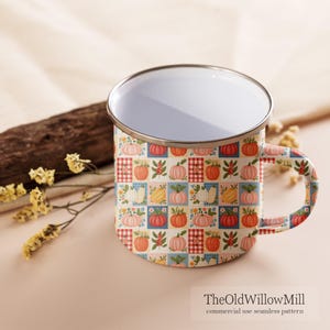 Puede incluir: Una taza de esmalte blanco con borde plateado y un patr&oacute;n de cuadr&iacute;cula repetitivo con calabazas coloridas, flores peque&ntilde;as y cuadrados a cuadros rojos y blancos. El texto TheOldWillowMill commercial use seamless pattern est&aacute; impreso.