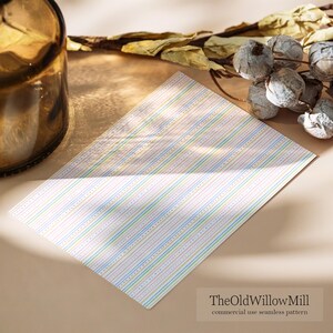 Puede incluir: Una hoja de papel rectangular con un patr&oacute;n repetitivo de finas rayas verticales en tonos pastel de azul, verde, amarillo y rosa, intercaladas con delicadas l&iacute;neas punteadas. El texto TheOldWillowMill commercial use seamless pattern es visible.