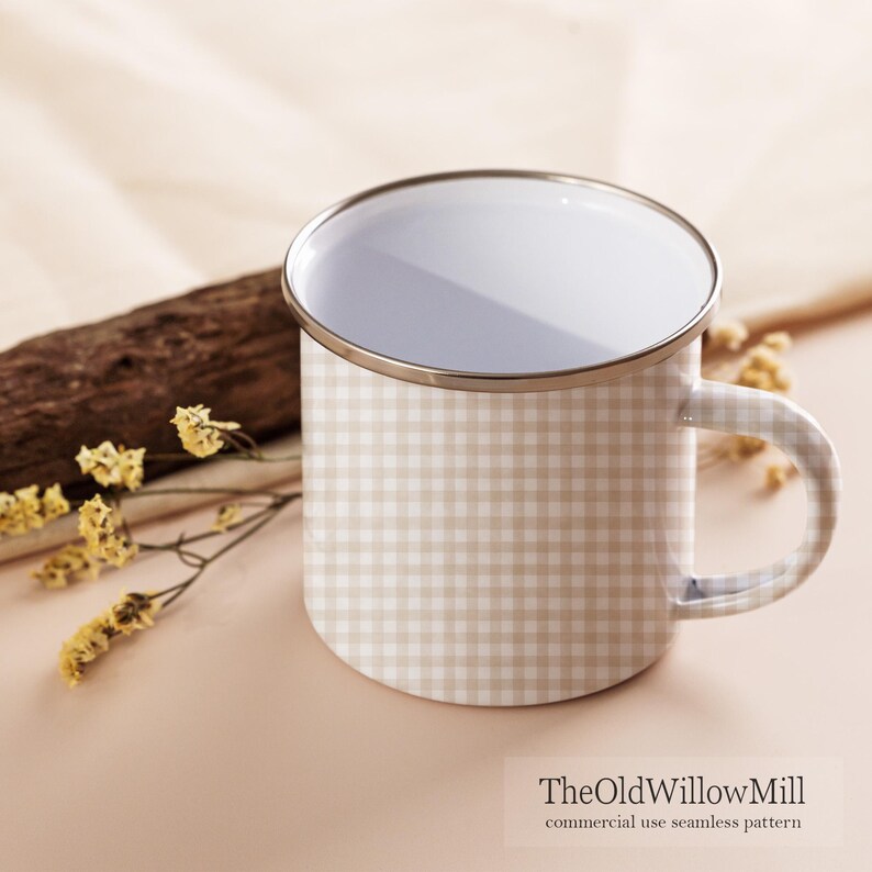 May include: A white enamel mug with a beige gingham pattern. The mug has a silver rim and handle. The Old Willow Mill logo is visible at the bottom. The mug is next to a piece of wood and some yellow flowers.