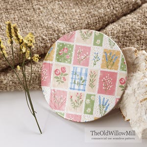 Puede incluir: Un posavasos circular con un dise&ntilde;o de patchwork de varias ilustraciones florales en tonos rosa, verde, amarillo y azul. El patr&oacute;n incluye rosas, margaritas y ramas de lavanda dispuestas en secciones de cuadr&iacute;cula rectangular.