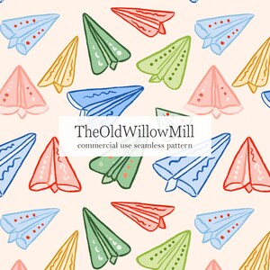 Puede incluir: Patrón sin costuras con aviones de papel de colores sobre un fondo crema. Los aviones son azules, verdes, amarillos, rosas y rojos. Se muestra el texto "TheOldWillowMill commercial use seamless pattern".