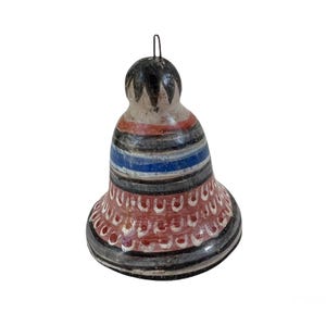 May include: A hand-painted ceramic bell with a black, red, and blue striped design. The bell has a white base and a black top with a pointed design.