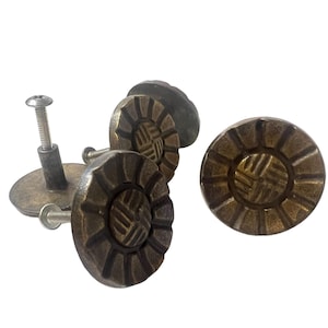 Könnte beinhalten: Vier antike Messing-Schrankknöpfe mit einem dekorativen, gewebten Design. Jeder Knopf hat eine runde Basis und eine erhabene, kreisförmige Mitte mit einem gewebten Muster. Die Knöpfe sind an Schrauben befestigt.