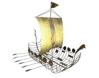 Pode incluir: Uma escultura de metal dourado de um navio viking com uma vela e remos. O navio é feito de arame e tem um design detalhado.