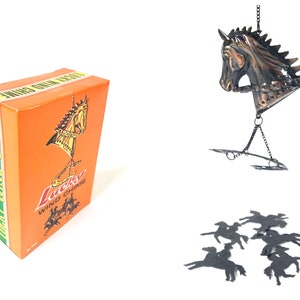 Può includere: Un carillon a vento Lucky con un design a forma di testa di cavallo. Il carillon è in metallo e ha una finitura marrone. La scatola è arancione con le parole "Lucky Wind Chime" stampate su di essa.