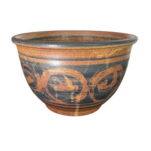 May include: A ceramic bowl with a wide rim and a rounded body. The bowl features a brown and black color scheme with a decorative pattern of swirling orange brushstrokes. The bowl is suitable for serving food or as a decorative piece.