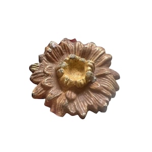 Könnte beinhalten: Eine braune und goldene Keramikblume mit einer erhabenen Mitte. Die Blume hat eine strukturierte Oberfläche und ist ein Dekorationsstück.