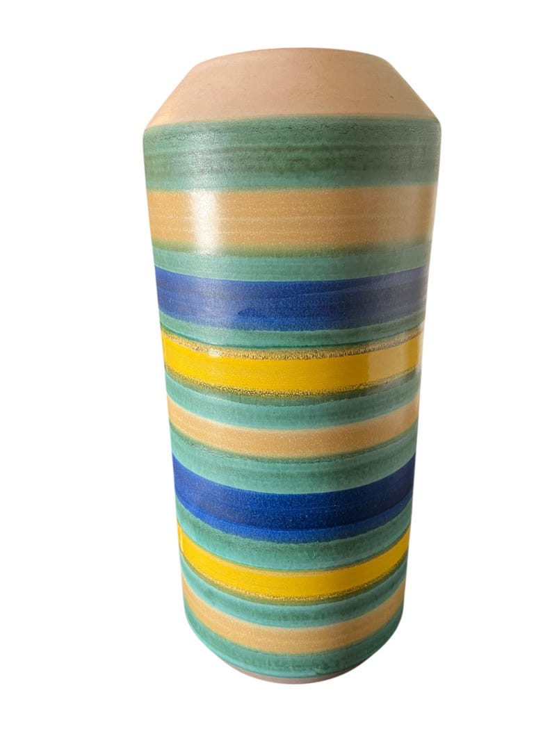 May include: A cylindrical ceramic vase with horizontal stripes in shades of beige, green, yellow, and blue. The vase has a slightly flared top and a smooth, glossy finish. The design is a modern take on a classic vase.
