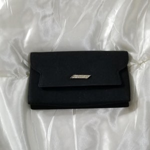 May include: A black velvet clutch purse with a silver clasp adorned with clear rhinestones.