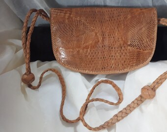 May include: A brown leather handbag with a braided strap. The bag has a textured, snakeskin-like pattern.