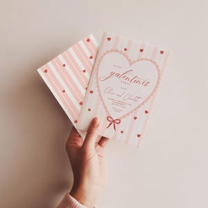 May include: A Galentine's Party invitation with a pink and white striped design. The invitation features a heart-shaped design with the words "Galentine's Party" and the names "Olivia and Charlotte". Small red hearts are scattered across the invitation.