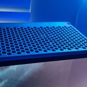 Peut inclure: Une étagère en plastique bleu avec un motif en nid d'abeille. L'étagère est conçue pour être montée sur un mur ou une autre surface.