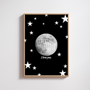 May include: A framed art print featuring a black background with white stars. A large moon graphic in the center has a bed illustration. The text "I love you" is below the moon. The frame is a light brown color.