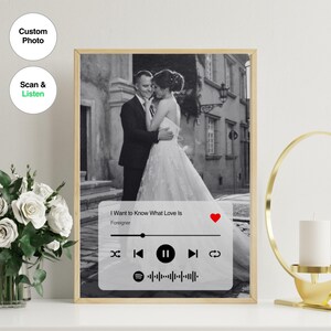 Puede incluir: Una foto en blanco y negro de una pareja en un entorno de boda, con una interfaz de reproductor de música debajo de la foto. El reproductor de música muestra la canción "I Want to Know What Love Is" de Foreigner.