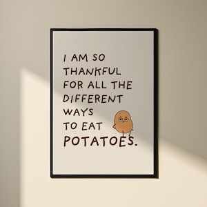 Puede incluir: Una impresión enmarcada en negro con fondo blanco y texto marrón que dice "Estoy tan agradecido por todas las diferentes formas de comer patatas." Una patata de dibujos animados con cara está sentada a la derecha del texto.