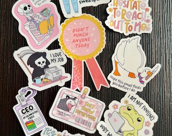 May include: A collection of humorous stickers with various designs and text. The stickers feature phrases like "Didn't punch anyone today," "I love my job," and "Very worky today." Other designs include a skeleton, a grim reaper, and a frog.