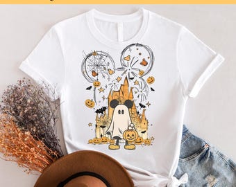 May include: White t-shirt featuring a black and white illustration of Mickey Mouse dressed as a ghost holding a pumpkin. The illustration is surrounded by pumpkins, bats, stars, and fireworks. The text "Ready to Press DTF Transfer" is at the top of the image.