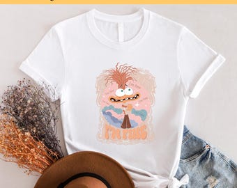 May include: White t-shirt with a cartoon character wearing a brown shirt and holding a microphone. The character is surrounded by clouds and the text "I'm Fine" is written in a retro font.