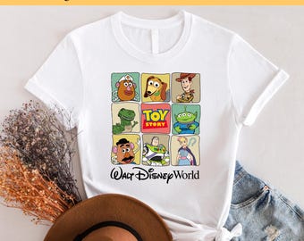 May include: White t-shirt with a colorful graphic of characters from the Toy Story movie franchise. The graphic includes Woody, Buzz Lightyear, Jessie, Rex, and Mr. Potato Head. The text "TOY STORY" and "WALT DISNEY WORLD" are also included in the graphic.