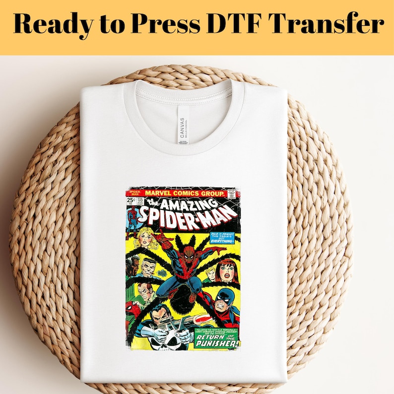 May include: White t-shirt with a vintage comic book print of The Amazing Spider-Man. The comic book cover features Spider-Man in a red and blue suit, fighting a group of villains. The text on the cover reads "The Amazing Spider-Man" and "Return of the Punisher!"