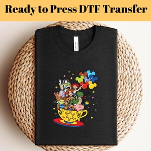 Pode incluir: Camiseta preta com um gr&aacute;fico dos personagens do Toy Story em uma x&iacute;cara de ch&aacute; com bal&otilde;es. Os personagens incluem Woody, Buzz Lightyear, Jessie, Rex, Hamm, Slinky Dog e Mr. Potato Head.