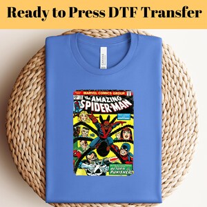 May include: A blue t-shirt with a vintage comic book print of The Amazing Spider-Man #105. The comic book cover features Spider-Man in action with the Punisher. The text on the comic book cover reads "The Amazing Spider-Man" and "Return of the Punisher!"