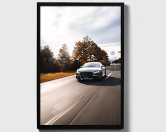 May include: A black car driving on a paved road through a forest. The car is moving fast, and the trees are blurred in the background. The sky is cloudy and the sun is shining.