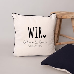 May include: White pillow with black text that reads "Wir" with a small heart symbol, "Celina & Toni", and "18.03.2025".