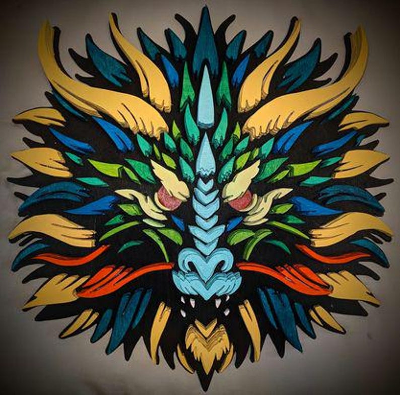 May include: A colorful, layered wooden dragon head sculpture. The dragon features a black base with accents of yellow, blue, green, and orange. The dragon's face is light blue with white teeth and red accents.
