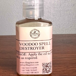 Op de afbeelding: Een kleine, transparante fles met een klapdop, gevuld met een bruine vloeistof. Het roze etiket draagt de tekst "VOODOO SPELL DESTROYER" en het merk "FIHAJ". Gebruiksaanwijzing en contactgegevens staan ook op het etiket.