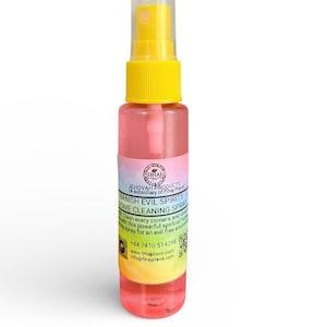 May include: A clear spray bottle with a yellow cap and a pink liquid. The label reads "BANISH EVIL SPIRITS HOME CLEANING SPRAY". The bottle is designed to cleanse and create an evil-free environment.