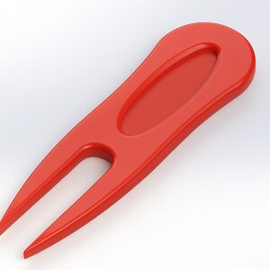 May include: A bright red golf divot repair tool. The tool has a rounded handle with an oval indentation and two pointed prongs. The tool is designed to repair divots on a golf course.