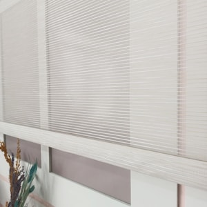 May include: A close-up of a white, horizontally striped window blind. The blind is partially lowered, showing a section of the window frame. The blind's texture is a fine, woven pattern, creating a soft, diffused light. The overall aesthetic is clean and modern.