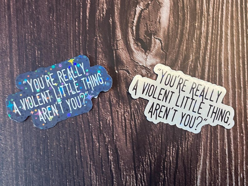 Pode incluir: Dois adesivos com o texto "You're really a violent little thing, aren't you?" Um adesivo &eacute; preto com glitter prata e o outro &eacute; prata com texto preto.