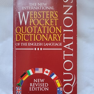 May include: A red book with the title "Webster's Pocket Quotation Dictionary" in white and yellow text. The cover features the word "Quotations" and flags of different nations. It is a new revised edition.