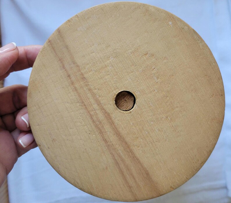 Puede incluir: Una base redonda de madera con un agujero en el centro. La base es de color marr&oacute;n claro y tiene una superficie lisa.