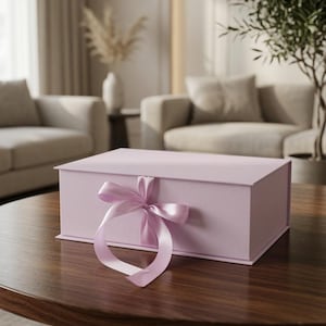 Può includere: Una scatola regalo rettangolare color lavanda chiaro con coperchio incernierato e un nastro di raso abbinato legato a fiocco nella parte centrale anteriore. La scatola presenta una finitura opaca liscia ed è costruita con bordi netti.