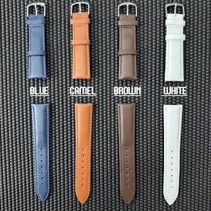 May include: An overhead shot displays four watch straps in blue, camel, brown, and white. Each strap is made of genuine leather and has a silver buckle. The word "BLUE", "CAMEL", "BROWN", and "WHITE" are printed below each strap. The words "GENUINE LEATHER" are printed at the bottom.