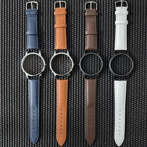 May include: Four watch faces with leather straps in blue, tan, brown, and white. The watch faces are silver and black. The straps have silver buckles and are arranged vertically against a textured black background.